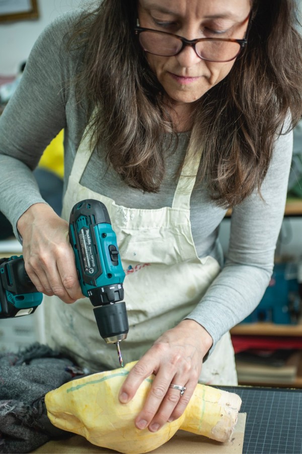 Tiina is drilling a hole in a puppet head