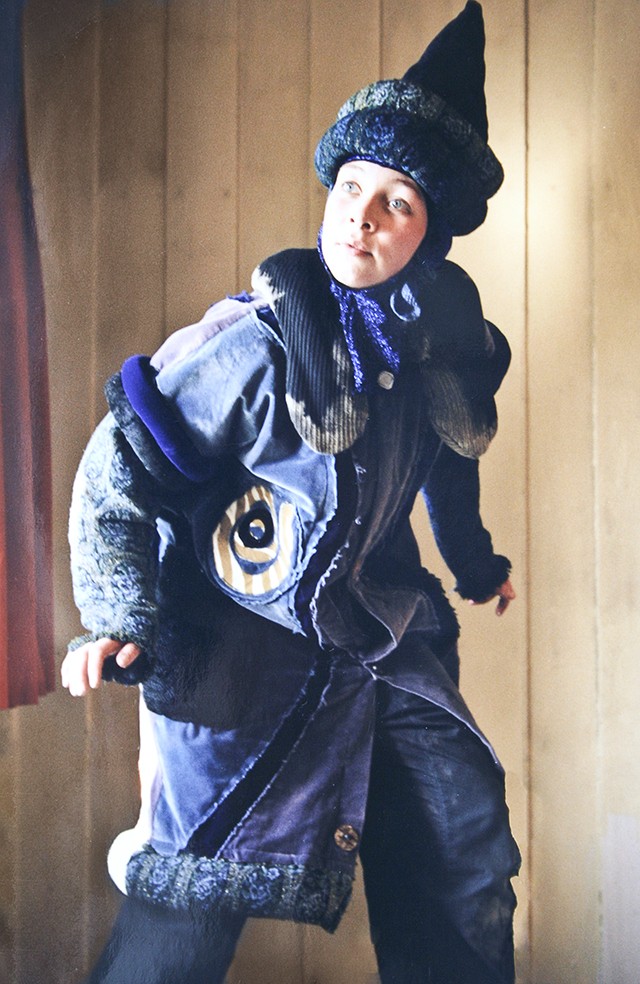An actress wearing the costume including a blue pointy hat and a blue, decorated coat